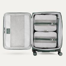Load image into Gallery viewer, Interior view of the suitcase showing two packing cubes held down by a set of adjustable straps. 
