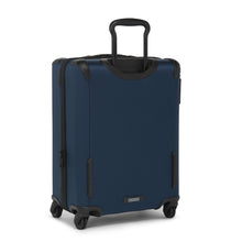 Load image into Gallery viewer, Angled back panel view of the blue suitcase. The telescopic handle is partly extended. 
