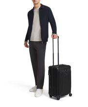 Load image into Gallery viewer, A young man holding his suitcase by the extended telescopic handle. 
