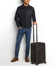 Load image into Gallery viewer, A model holding the suitcase by the telescopic handle.

