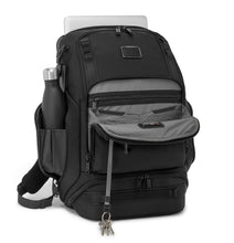 Load image into Gallery viewer, Angled Front panel view of the backpack. The front panel is unzipped. A set of keys is hanging from the included key chain cord, a water bottle is fitted inside the side panel&#39;s compartment, and a laptop is peeking from the back pocket. 
