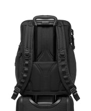 Load image into Gallery viewer, A suitcase&#39;s telescopic handle slid through the back strap of the backpack&#39;s attachment feature, which holds it in place. 
