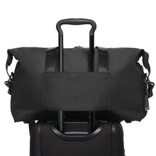 Load image into Gallery viewer, Back panel view of the satchel bag with the attachment feature shown. This allows for a telescopic handle of a suitcase to slide through and keep the bag in place. 
