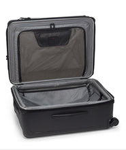 Load image into Gallery viewer, The black suitcase laid on its back with the front panel opened and lifted. The front panel has a zipper-closing compartment on the interior. There are other organizational pockets inside.
