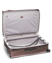 Load image into Gallery viewer, Interior view of the blush suitcase. The lining is light gray, and the front panel has a zipper-closing divider with a pocket. The back panel has a set of straps to hold your contents in place. 
