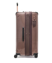 Load image into Gallery viewer, Side panel view of the blush colored suitcase with the expandable feature unzipped. It features a grab handle, and a tag.
