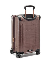 Load image into Gallery viewer, Angled back panel view of the blush suitcase with black accents. 
