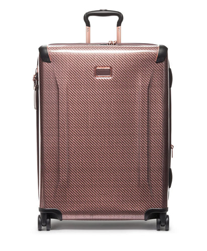 Front panel view of the blush colored suitcase with black accents. The telescopic handle is partly extended. 