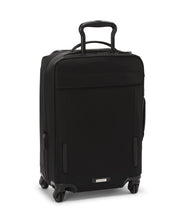 Load image into Gallery viewer, Angled back panel view of the black suitcase with the telescopic handle partly extended. 
