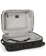 Load image into Gallery viewer, The suitcase laid on its back with the main compartment unzipped and lifted. The back panel interior has a set of straps to hold contents in place, and the front panel a set if zipper pockets. 
