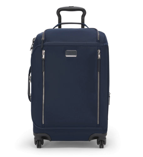 A navy blue TUMI carry-on suitcase with a telescoping handle and multiple zippered compartments.