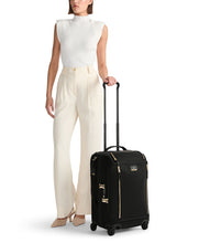 Load image into Gallery viewer, A young woman holding her Tumi suitcase by the extended telescopic handle. 
