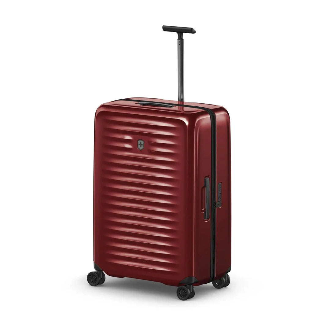 Angled front view of the red hard side suitcase with the telescopic handle extended. 
