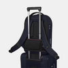 Angled back panel view of the backpack with the attachment straps holding it to the telescopic handle of a suitcase. 