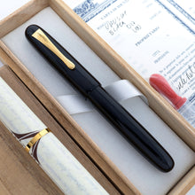 Load image into Gallery viewer, The image shows the front-side of the Visconti Black Urushi with its cap on, laying in its original box with the included items. 
