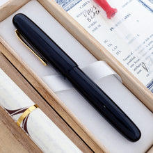 Load image into Gallery viewer, The image shows the other side of the Visconti Black Urushi with its cap on, laying in its original box with the included items. 
