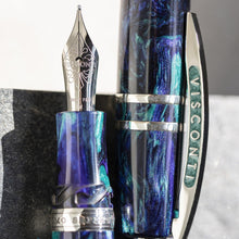Load image into Gallery viewer, Close up to the Visconti Earth Origins Water Fountain Pen and cap. The body is made of royal blue, turquoise and black resin swirls, and light metal trims. 
