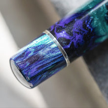 Load image into Gallery viewer, Close up to the bottom of the Earth Origins Pen. It has a stainless steel ring where the piston meets the pen. The pen is made with black royal blue, and turquoise swirls of lacquer. 
