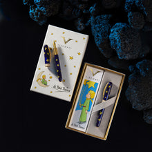 Load image into Gallery viewer, Two Visconti fountain pens with deep blue bodies and gold stars are shown with their branded boxes on a dark background with blue rock props. 
