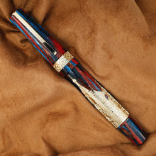 Load image into Gallery viewer, Decorative pen with red, blue, and gold accents on a brown fabric background

