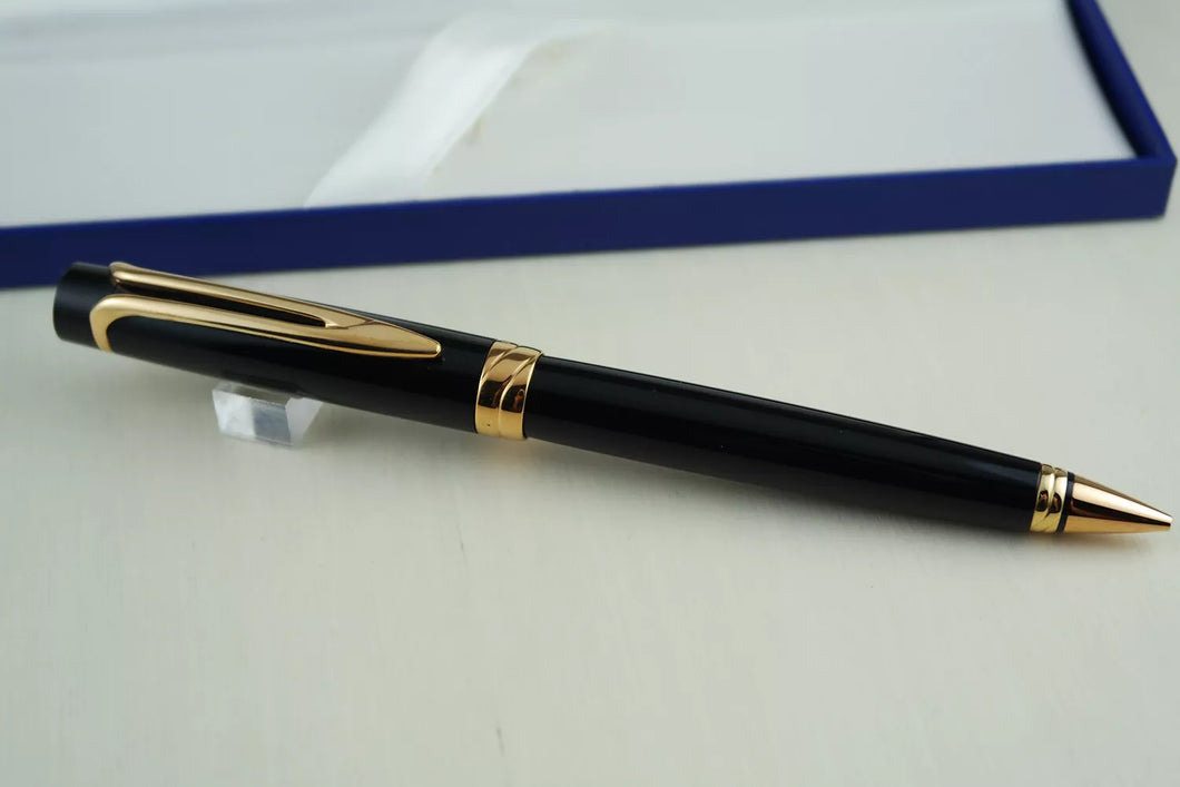 Front view of the mechanical pencil. It has a black barrel with gold-plated accents on the clip, center ring, and the nose section.