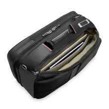 Load image into Gallery viewer, Angled side panel view of the black backpack duffle. The back panel's compartment is unzipped is opened and a laptop and tablet are stored in the padded organizers.
