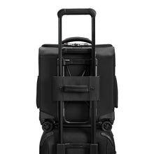 Load image into Gallery viewer, Back panel view of the black underseat cabin spinner suitcase. The interlocking handle is turned and attaching it to the handles of a suitcase. 
