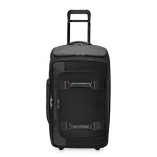 Load image into Gallery viewer, Front panel view of the black wheeled duffle. It features two grip handles and a zipper-closing pocket at the top. The telescopic handle is extended. 
