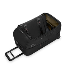 Load image into Gallery viewer, Angled view of the black duffle bag laid on the back panel. The main compartment is unzipped and the lid has toppled inside. 
