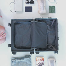 Load and play video in Gallery viewer, A young woman arranging two packing cubes into a carry-on suitcase. 
