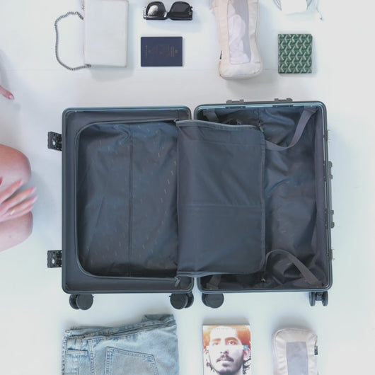 A young woman arranging two packing cubes into a carry-on suitcase. 