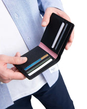 Load image into Gallery viewer, A Black Roy Wallet with credit cards being held by two hands.
