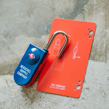 Load image into Gallery viewer, The navy blue lock arranged with the orange key card on a textured gray background.
