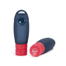 Load image into Gallery viewer, Two navy blue travel bottles with red caps arranged on a white background. 
