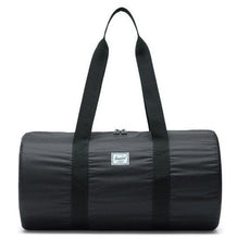 Load image into Gallery viewer, Front view of the black packable duffle bag with the shoulder straps lifted.
