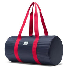 Load image into Gallery viewer, Angled front view of the navy red duffle bag with the shoulder straps pulled up.

