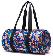 Load image into Gallery viewer, Angled front view of the Painted Floral Packable duffle with the black shoulder straps pulled up.
