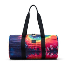Load image into Gallery viewer, Front view of the Rainbow Tie-Dye duffle bag with the black shoulder straps pulled up.
