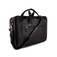 Load image into Gallery viewer, Angled front view of the brown leather briefcase with the shoulder strap laid across the front.
