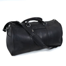 Load image into Gallery viewer, Angled front view of the black duffle bag. The removable shoulder strap is resting across the top and front.
