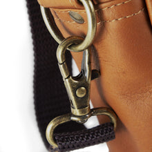 Load image into Gallery viewer, Close up to the briefcase side panel brass ring attached to the shoulder strap's trigger snap.
