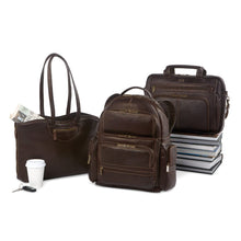 Load image into Gallery viewer, A tote bag, backpack, and briefcase in matching brown leather, arranged on a white background with a coffee cup, newspaper, car keys, and books. 
