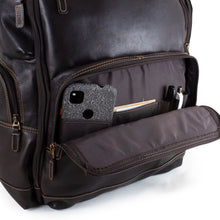 Load image into Gallery viewer, Close up to the front panel of the backpack. The  bottom pocket is opened. A cellphone, business cards, and two pens are arranged inside. 
