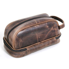 Load image into Gallery viewer, Angled back view of the brown distressed leather toiletry bag. 
