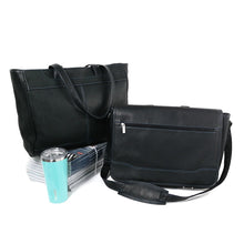 Load image into Gallery viewer, A tote bag and messenger bag in black leather with blue stitching arranged on a white background with magazines and a blue cup.
