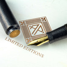 Load image into Gallery viewer, Close up to the Fountain pen nib with the cap set next to it. Both are placed on top of the white outer box which features the AP Logo embossed with gold foil on it. 
