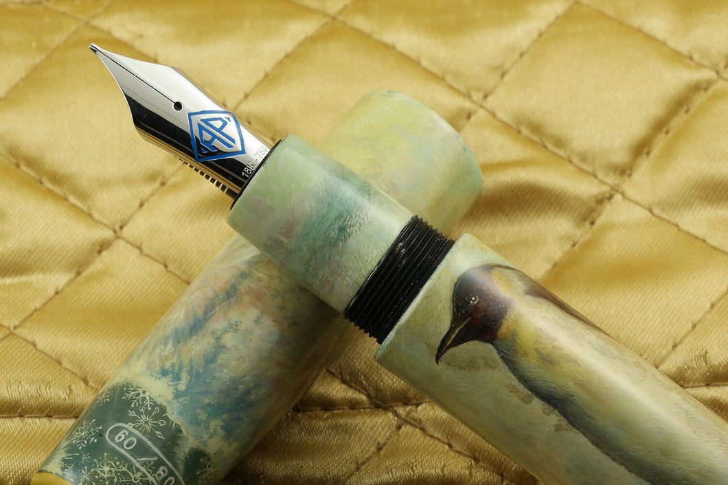 Close up to the Fountain Pen nib set on top of the cap. Placed on top of a golden fabric. The nib is made of 18K-750 white gold, and features the AP Limited Editions logo in blue.