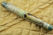 Load image into Gallery viewer, View of the Fountain Pen with the cap on. Placed on top of a golden fabric. 
