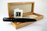 View of the rollerball pen with the included wooden case and tag. Set on a white background.