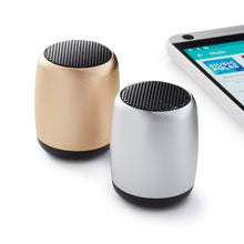 Load image into Gallery viewer, Two cylindrical Bluetooth wireless speakers, one in gold and one in silver, next to a smartphone.

